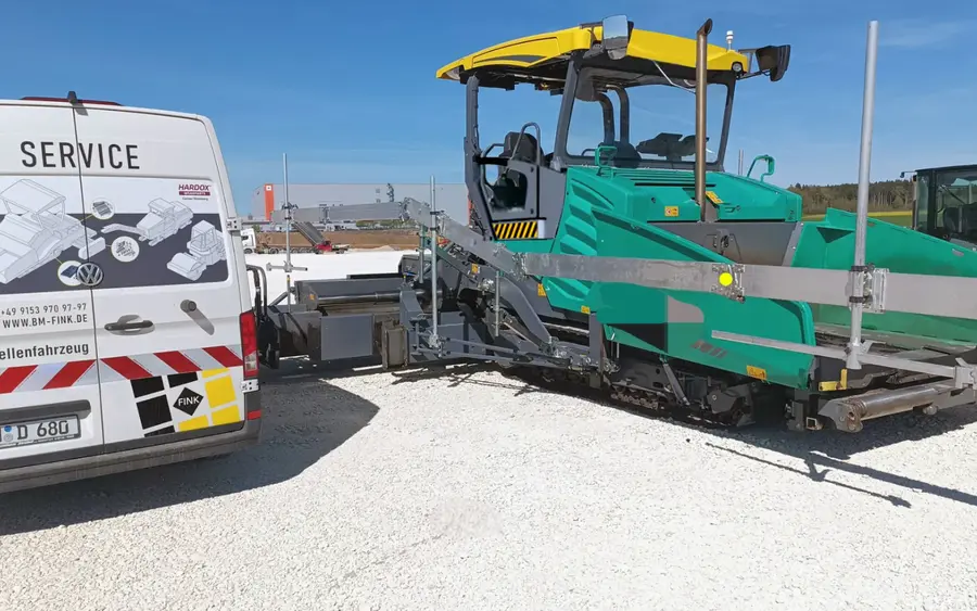 FINK Servicemobil neben einem Straßenfertiger auf der Baustelle